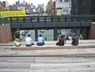 People sitting on wooden steps watching the traffic below